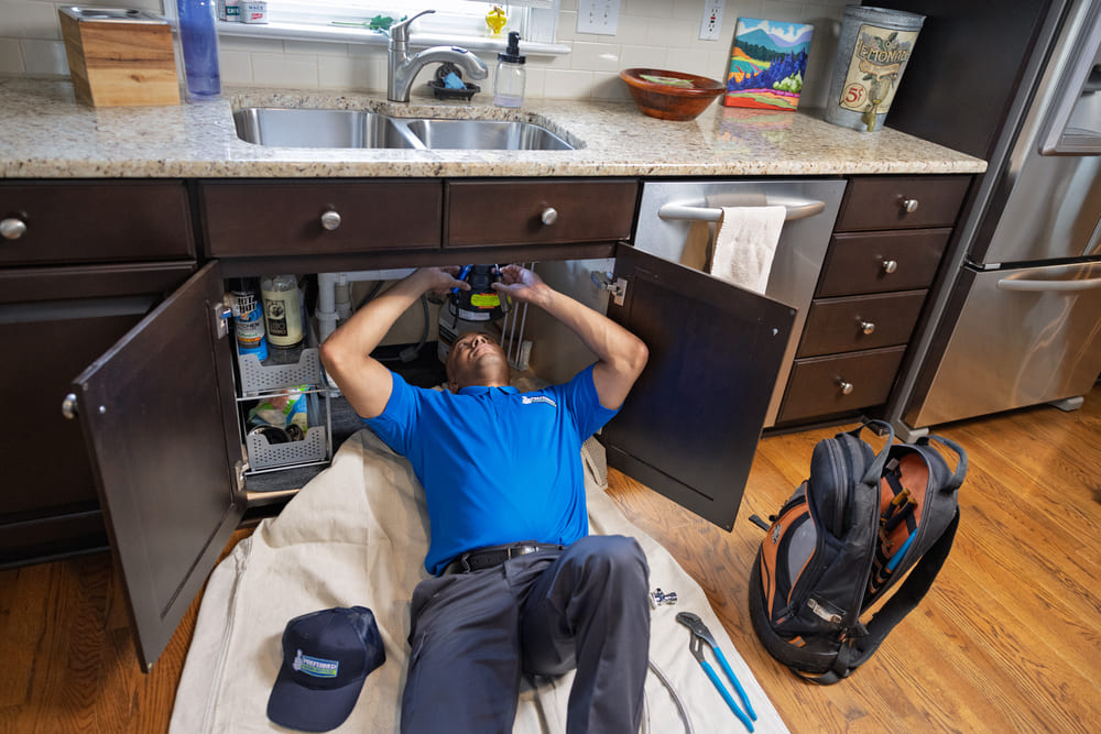A camera inspection setup for a sewer line under a Bowden home with the technician watching the monitor